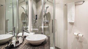 Une salle de bain moderne avec une douche à parois de verre, deux lavabos et un porte-serviettes.