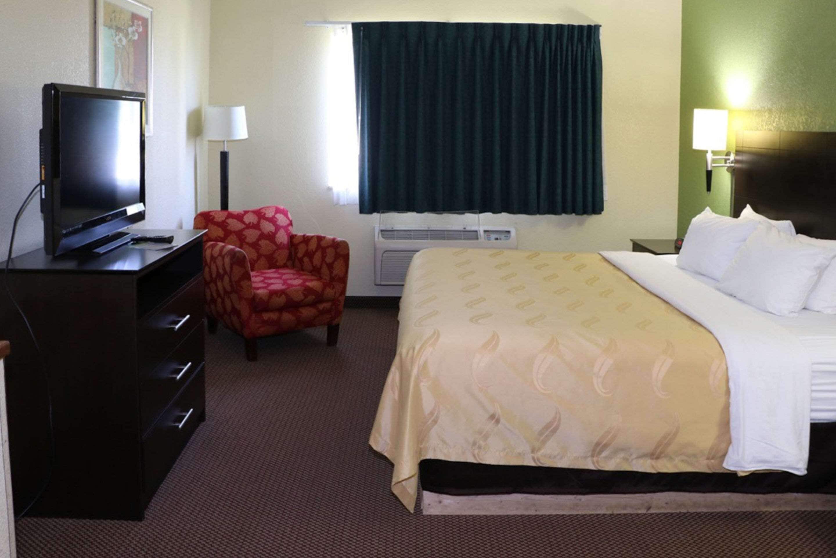 Une chambre d’hôtel équipée d’un lit, d’une télévision, d’une chaise, d’un bureau et d’un appareil de climatisation.