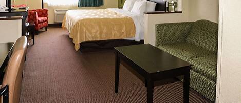 Une chambre d’hôtel avec un lit, un bureau, une chaise, un canapé vert et un téléviseur.