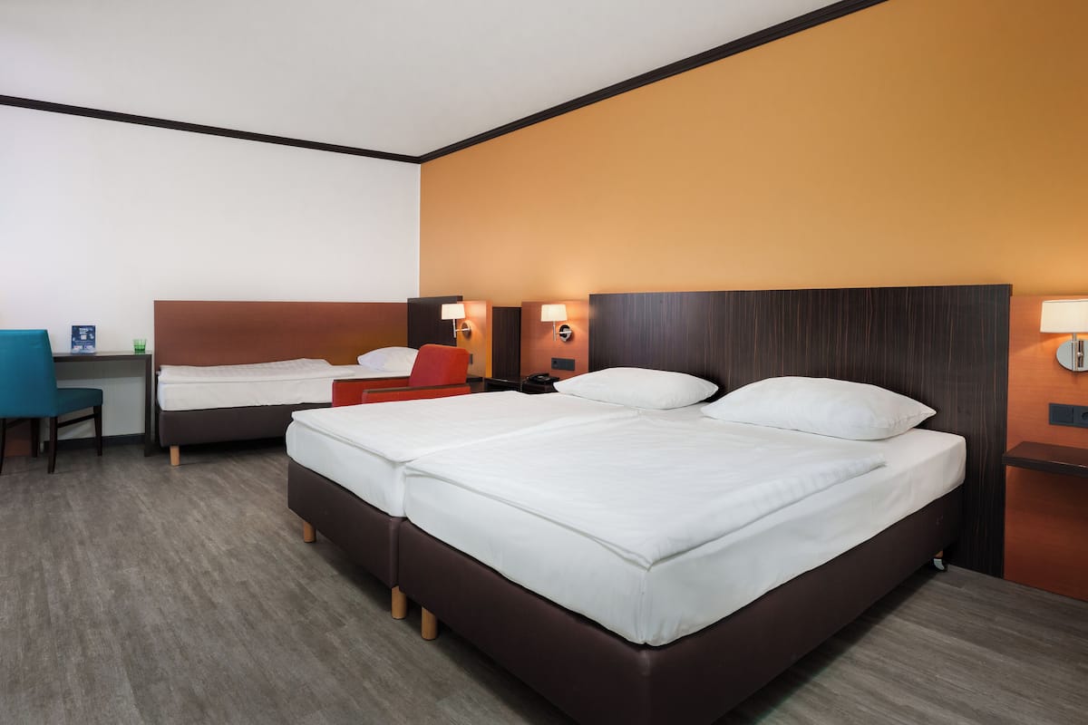 A hotel room with two beds, a desk, and a chair.