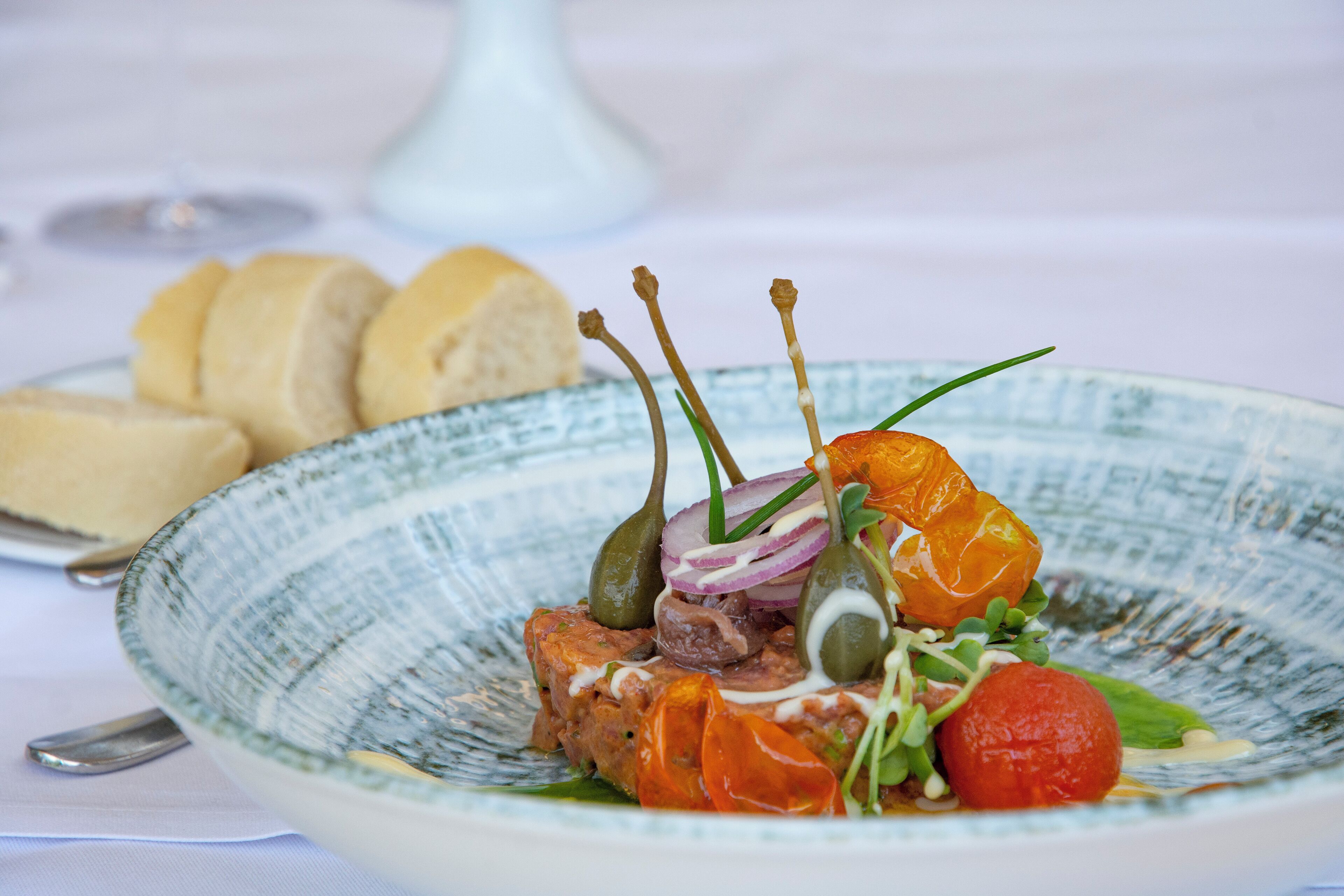 A plate of food with bread and a white vase in the background.