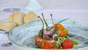 A plate of food with bread and a white vase in the background.