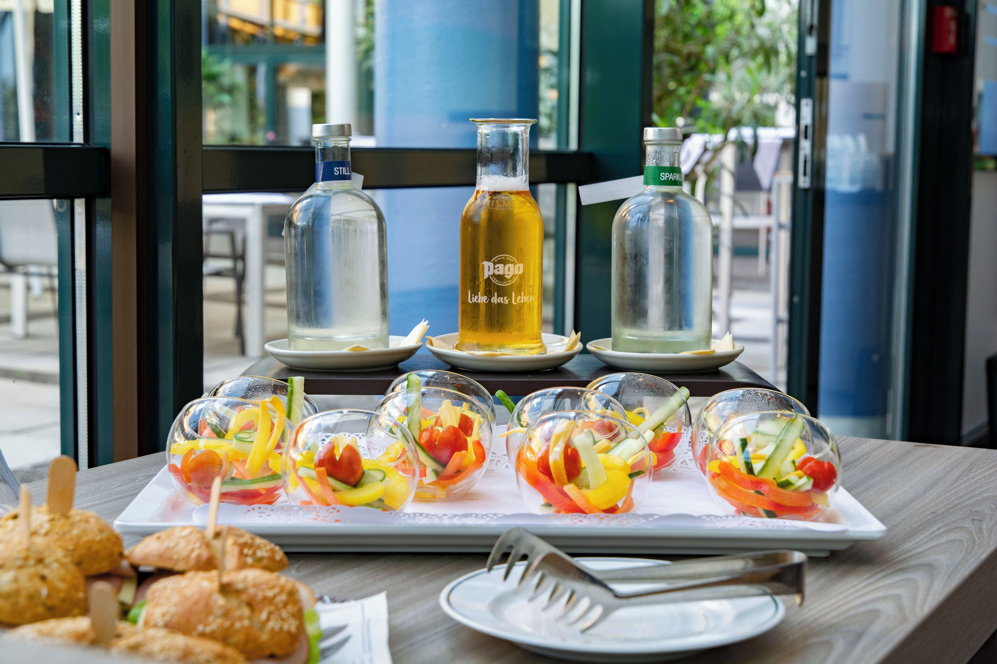 A table with a variety of food items, including sandwiches and fruit salads, and two bottles of beverages.