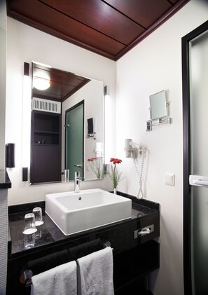 Un baño moderno con un espejo grande, un lavabo blanco y un secador de pelo.
