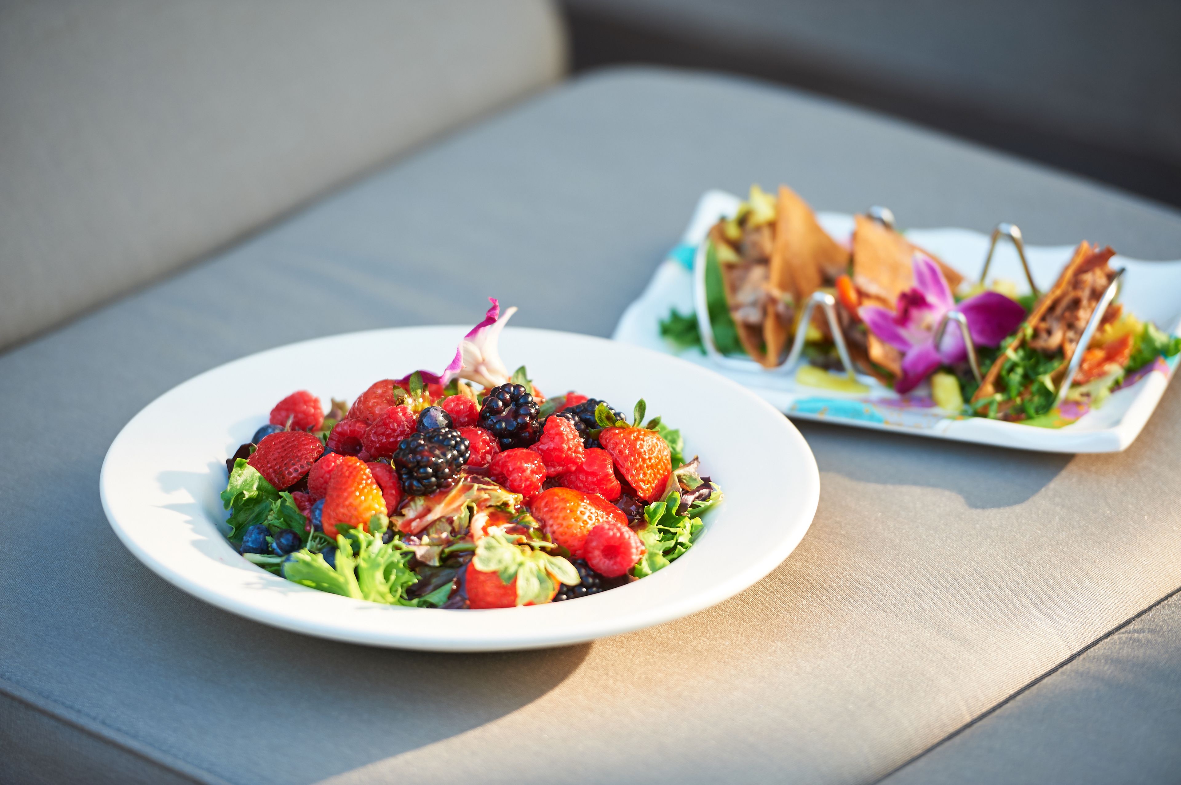 A plate of mixed berries and greens on a table.