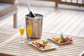 A breakfast setting with a bottle of champagne in a bucket, two glasses of orange juice, and plates of toast, eggs, and pancakes. - DoubleTree by Hilton Dallas - Market Center (Dallas)