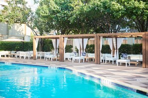 Un espace aménagé au bord de la piscine, avec des chaises longues et une pergola recouverte de tissu.