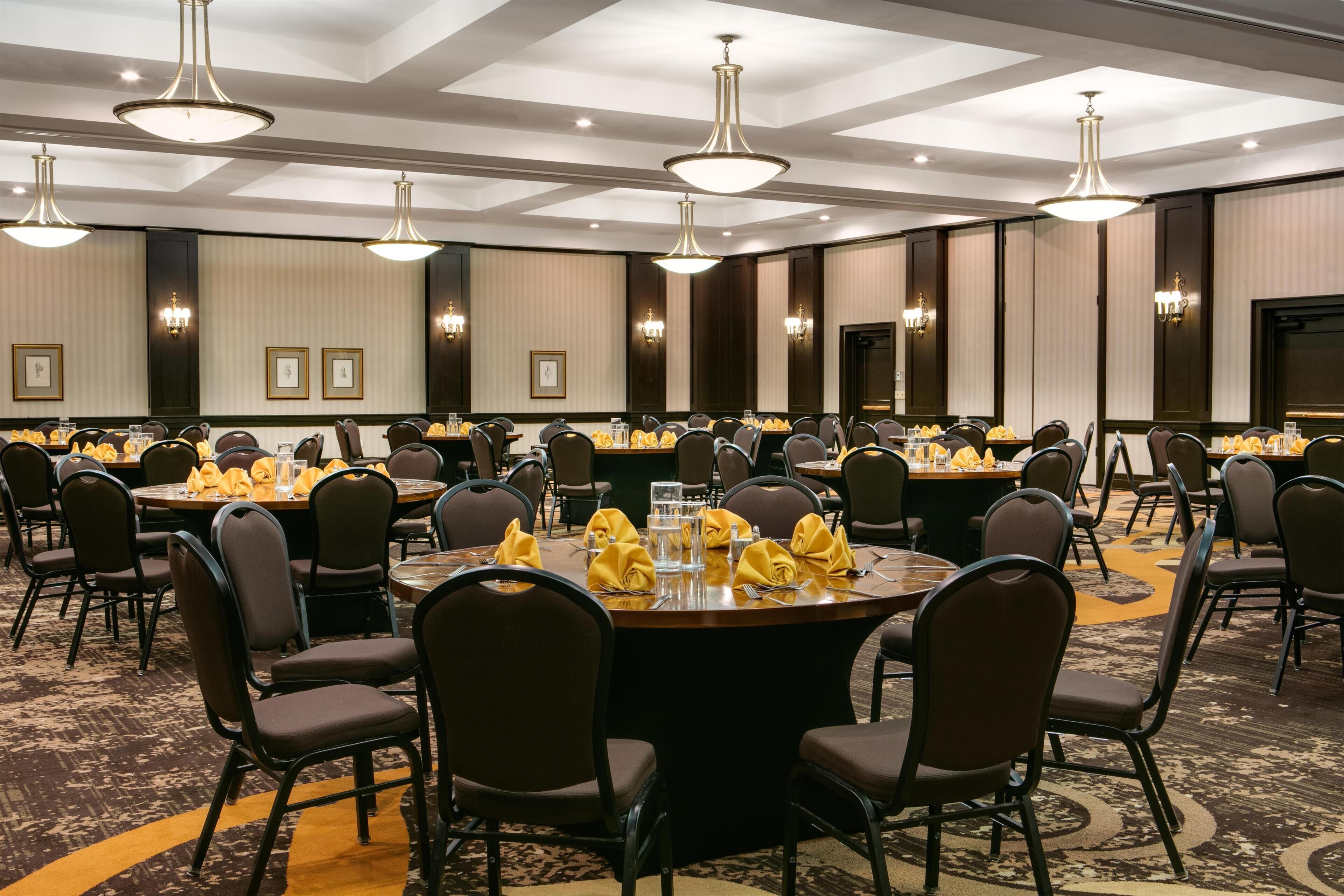 A conference room with round tables, chairs, and chandeliers.