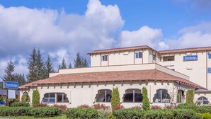 A two-story building with a Travelodge sign, featuring a tiled roof and arched windows. - Travelodge by Wyndham Juneau (Juneau)