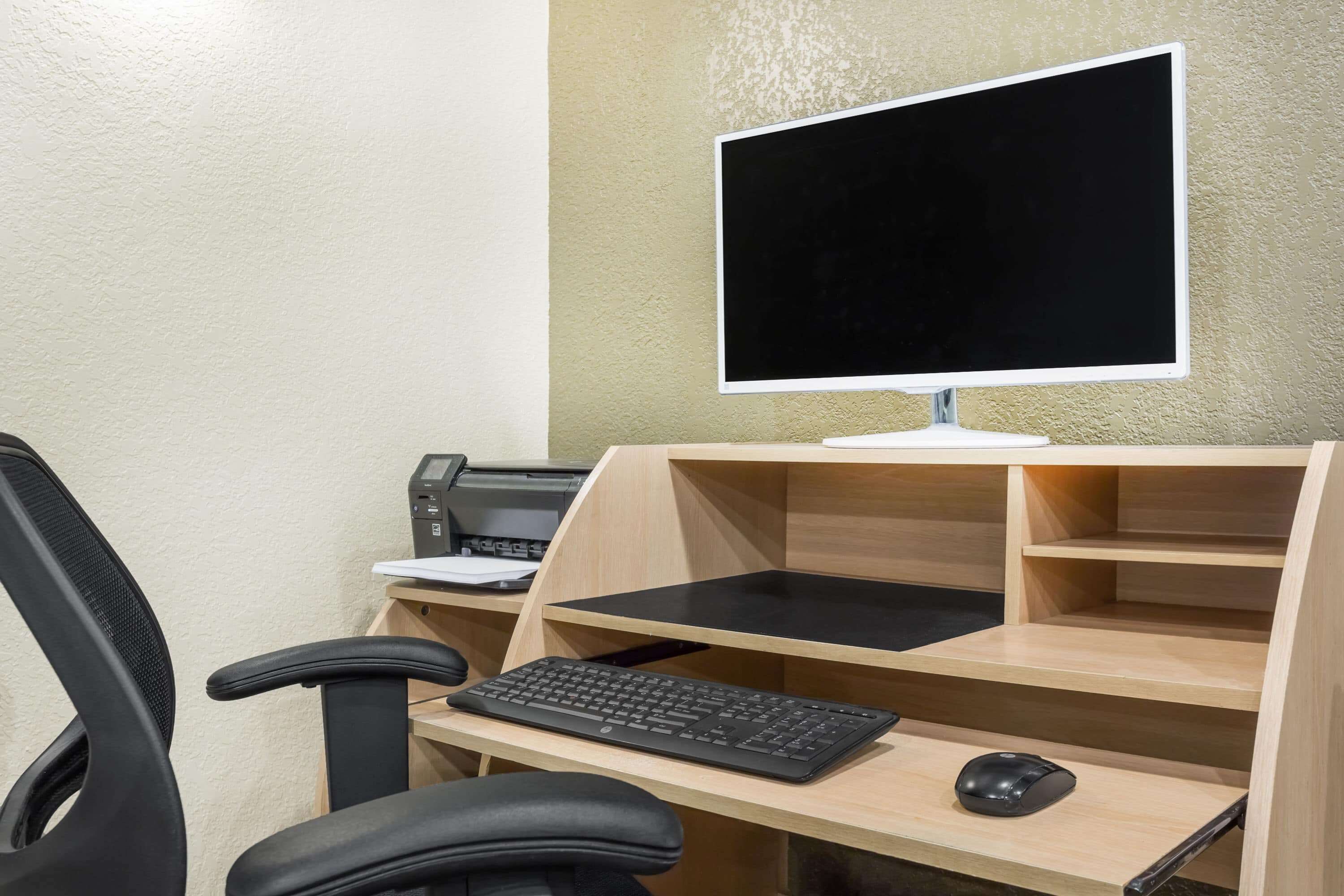 Una scrivania moderna con un monitor per computer, tastiera e mouse.