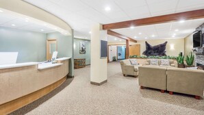 A reception area with a curved desk, a sofa set, and a large wall-mounted sculpture. - Travelodge by Wyndham Juneau (Juneau)