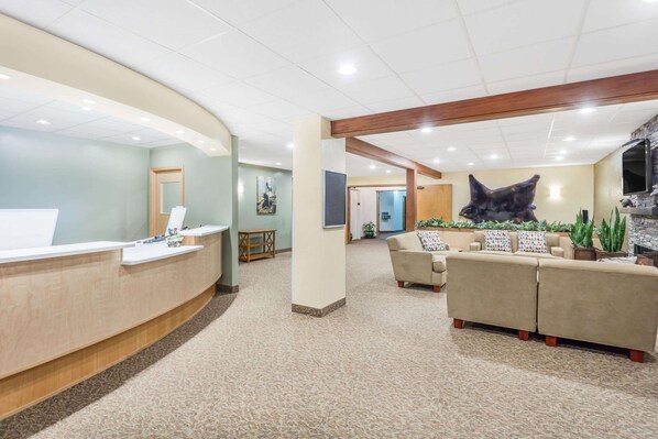 A reception area with a curved desk, a sofa set, and a large wall-mounted sculpture. - Travelodge by Wyndham Juneau (Juneau)