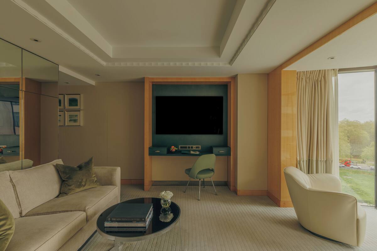 A modern living room with a sofa, a chair, a coffee table, a flat-screen TV, and a desk with a computer.