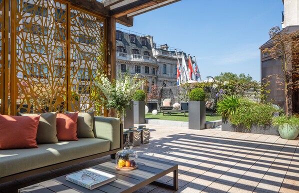 Relax in this inviting outdoor seating area with a sofa, coffee table, and lush greenery.