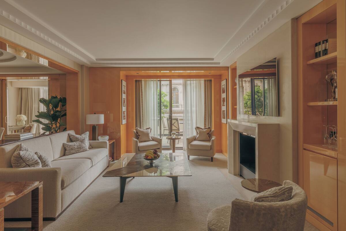 A well-lit living room with a sofa, armchairs, a coffee table, and a fireplace.