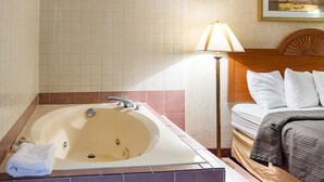 A hotel room with a large bathtub, a bed with white bedding, and a lamp. - Quality Inn Petersburg Fort Lee Area (Petersburg)