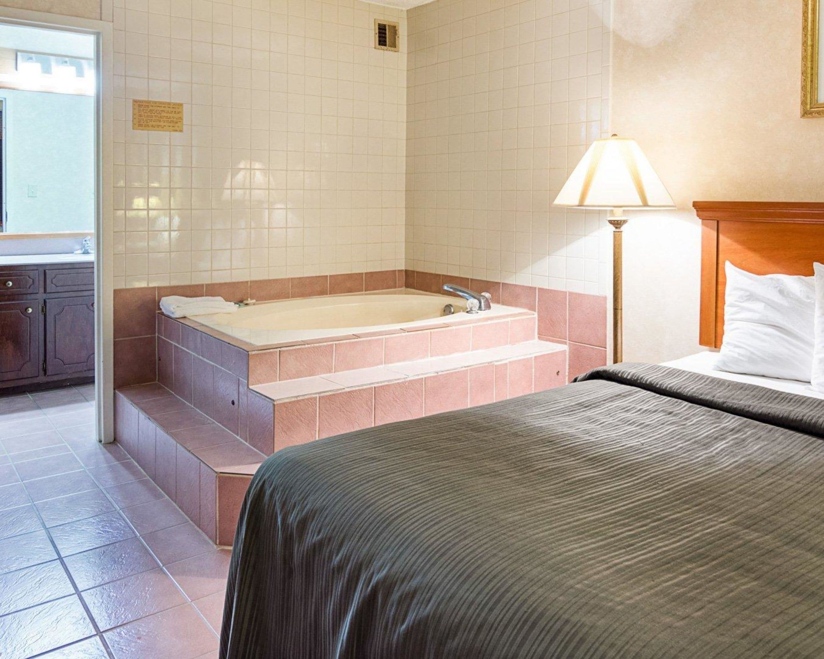 Habitación de hotel con una cama grande, una bañera y un baño pequeño.