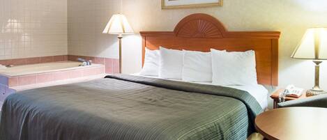 Habitación de hotel con una cama grande, una zona de estar, una bañera y un cuadro en la pared.