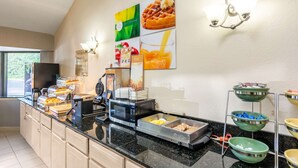 A breakfast buffet with various food items, a microwave, and a coffee machine. - Quality Inn Petersburg Fort Lee Area (Petersburg)