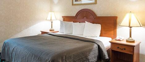 A hotel room with a large bed, two bedside tables with lamps, a framed picture on the wall, and a green carpet.
