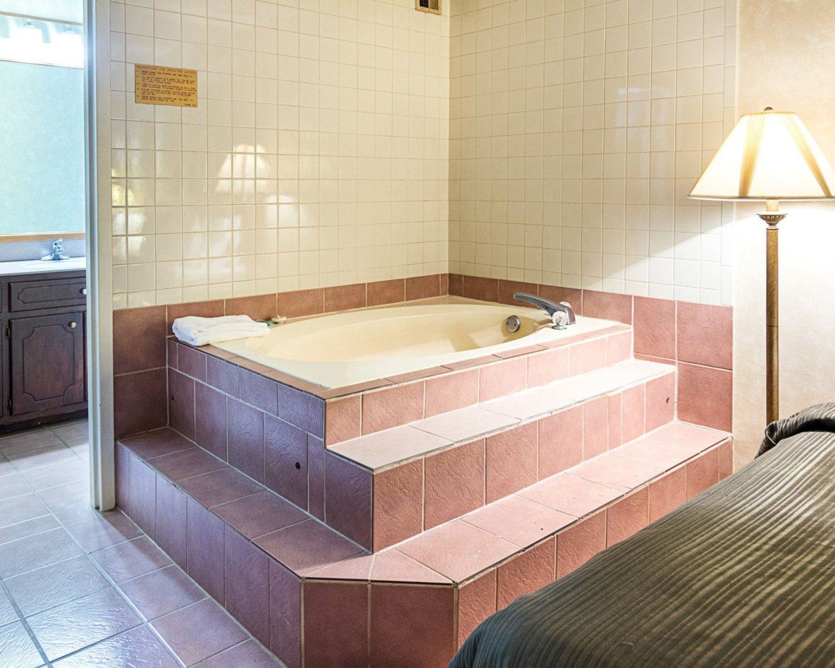 A bathroom with a bathtub, a sink, and a lamp.