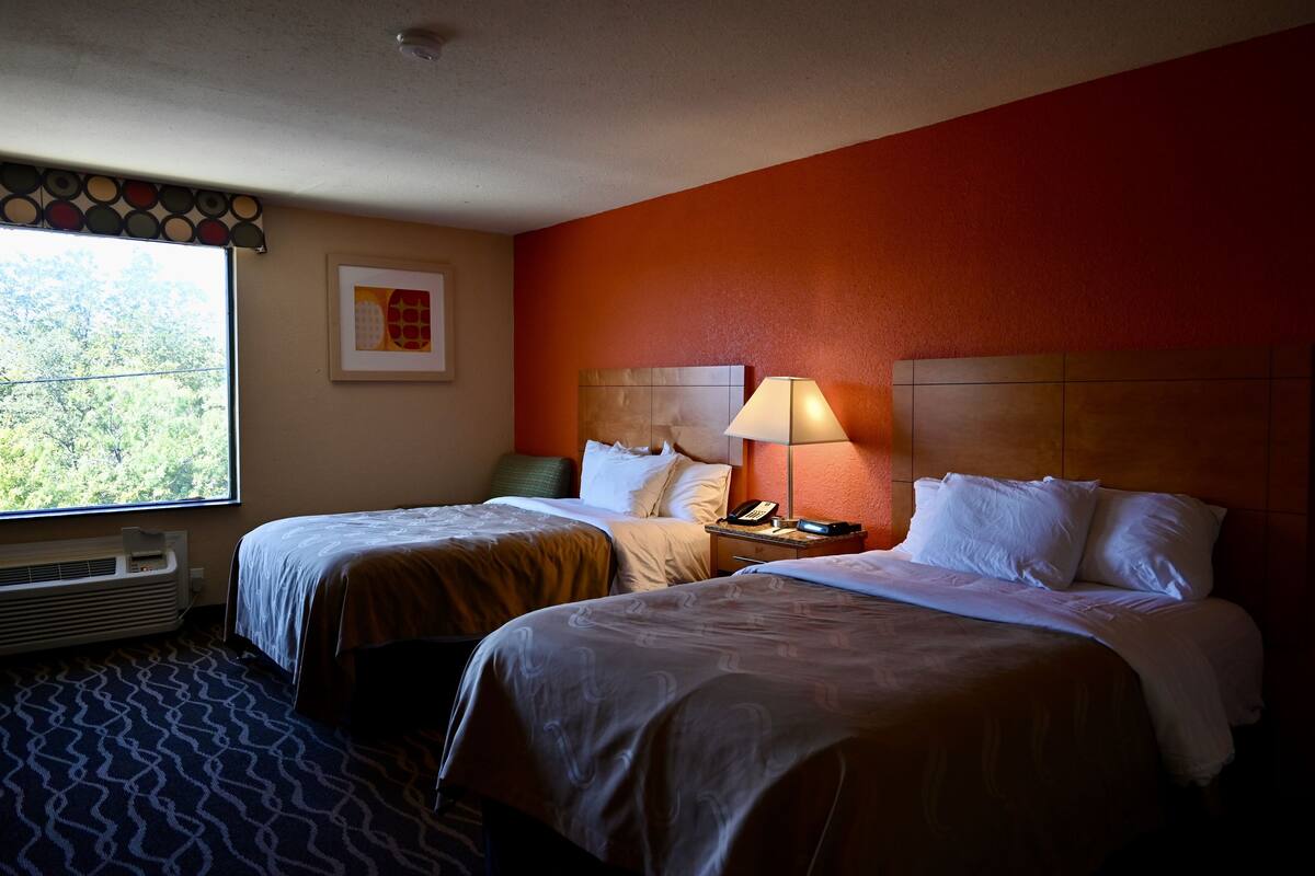 Ein Hotelzimmer mit zwei Betten, einem Heizgerät, einem Fenster mit Blick und einer Lampe.