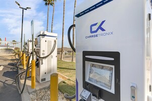 Une borne de recharge pour véhicules électriques de la marque ChargeTronix, dotée d’un écran numérique et d’un câble qui y est connecté.