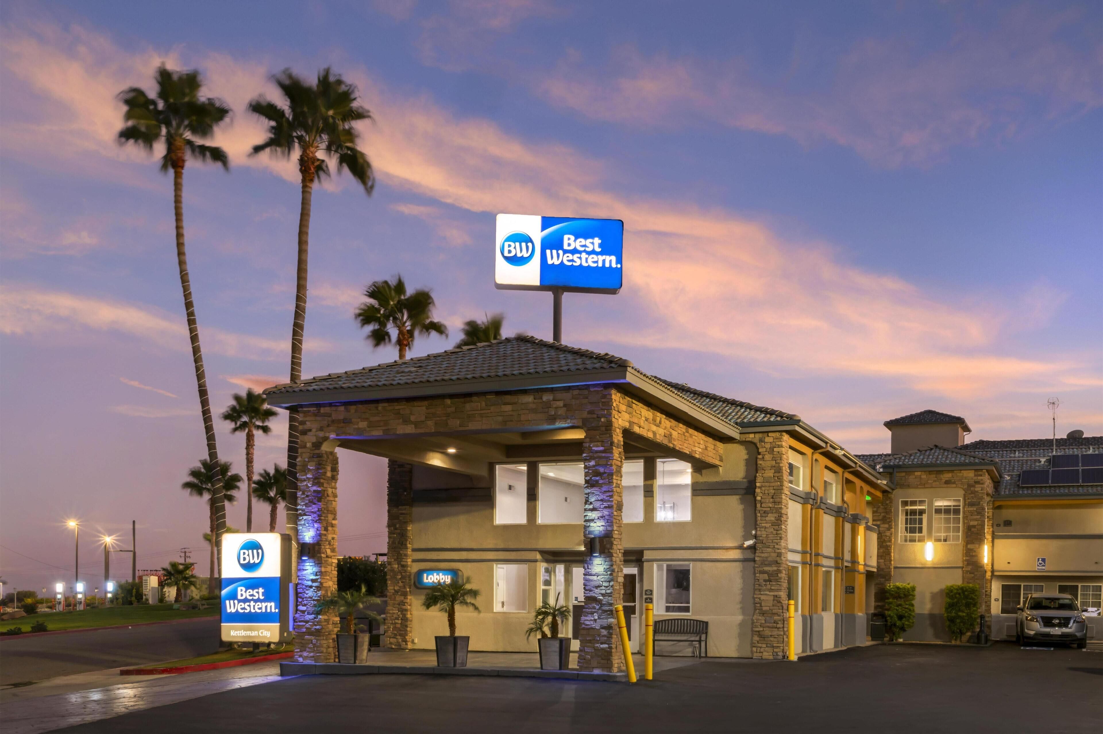 A Best Western hotel with a lobby entrance, palm trees, and a clear sky.