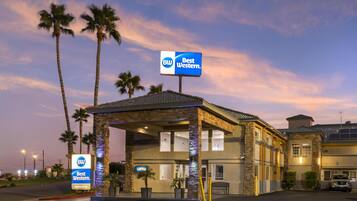 A Best Western hotel with a lobby entrance, palm trees, and a clear sky.