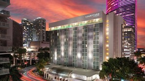 A modern hotel with a prominent 'Courtyard by Marriott' sign, large windows, and a curved roof structure. - Courtyard by Marriott Miami Downtown (Miami)