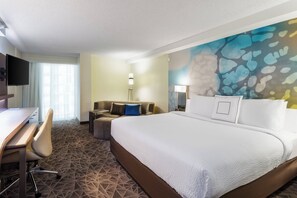 Une chambre d’hôtel avec un grand lit, un bureau, une chaise, un canapé et une télévision.
