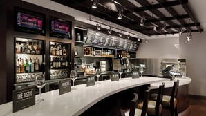 A bar area with multiple liquor displays, bar stools, and a long counter. - Courtyard by Marriott Miami Downtown (Miami)