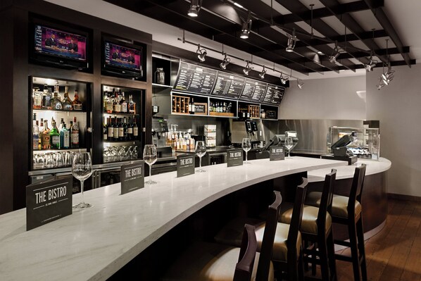 A bar area with multiple liquor displays, bar stools, and a long counter. - Courtyard by Marriott Miami Downtown (Miami)