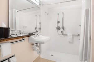 A modern bathroom with a sink, mirror, and shower.