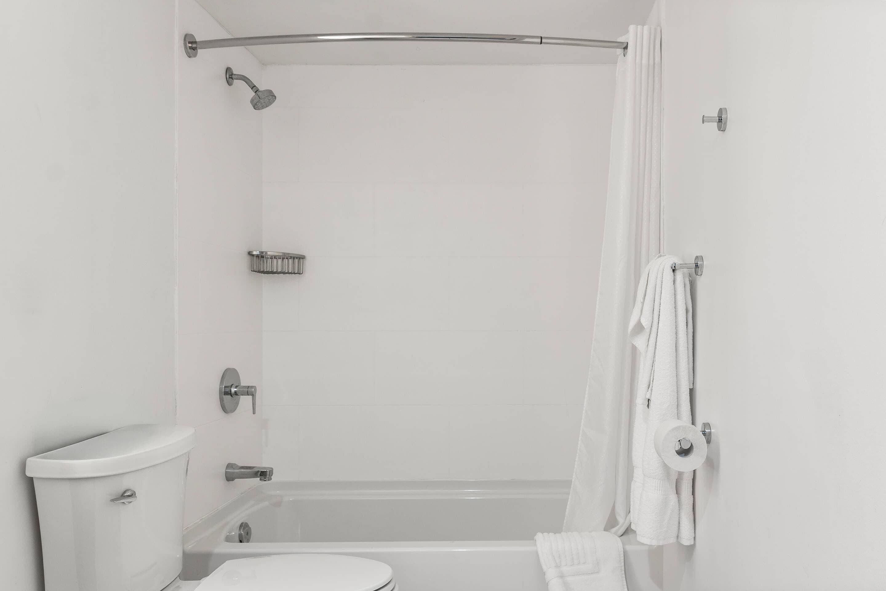 Un baño con inodoro, bañera, ducha y un perchero para toallas.
