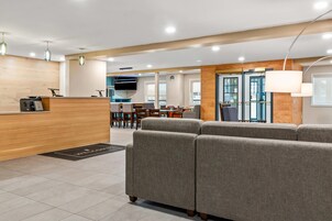 A modern hotel lobby with a reception desk, seating area, and a dining space.