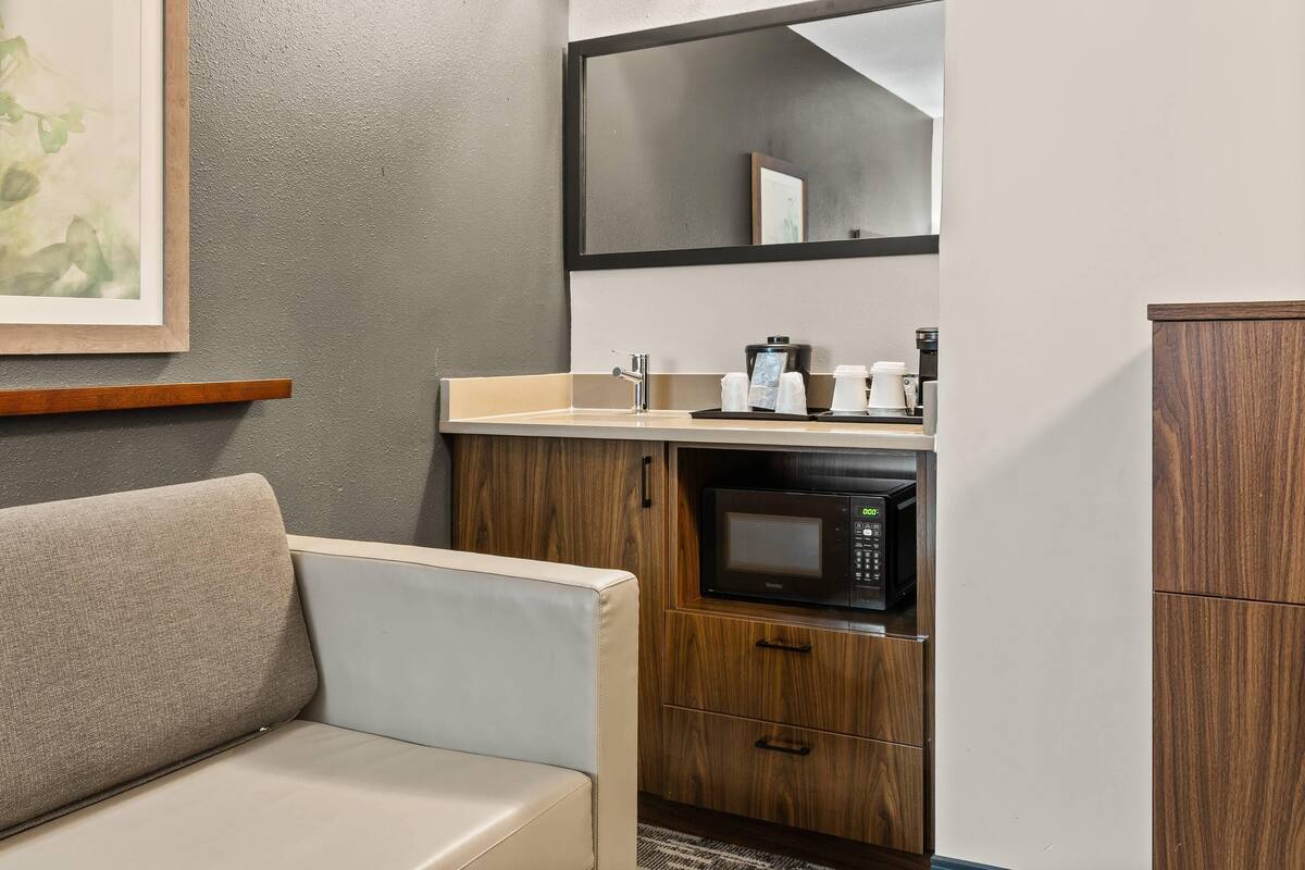 A compact kitchenette with a microwave, coffee maker, and cabinet.