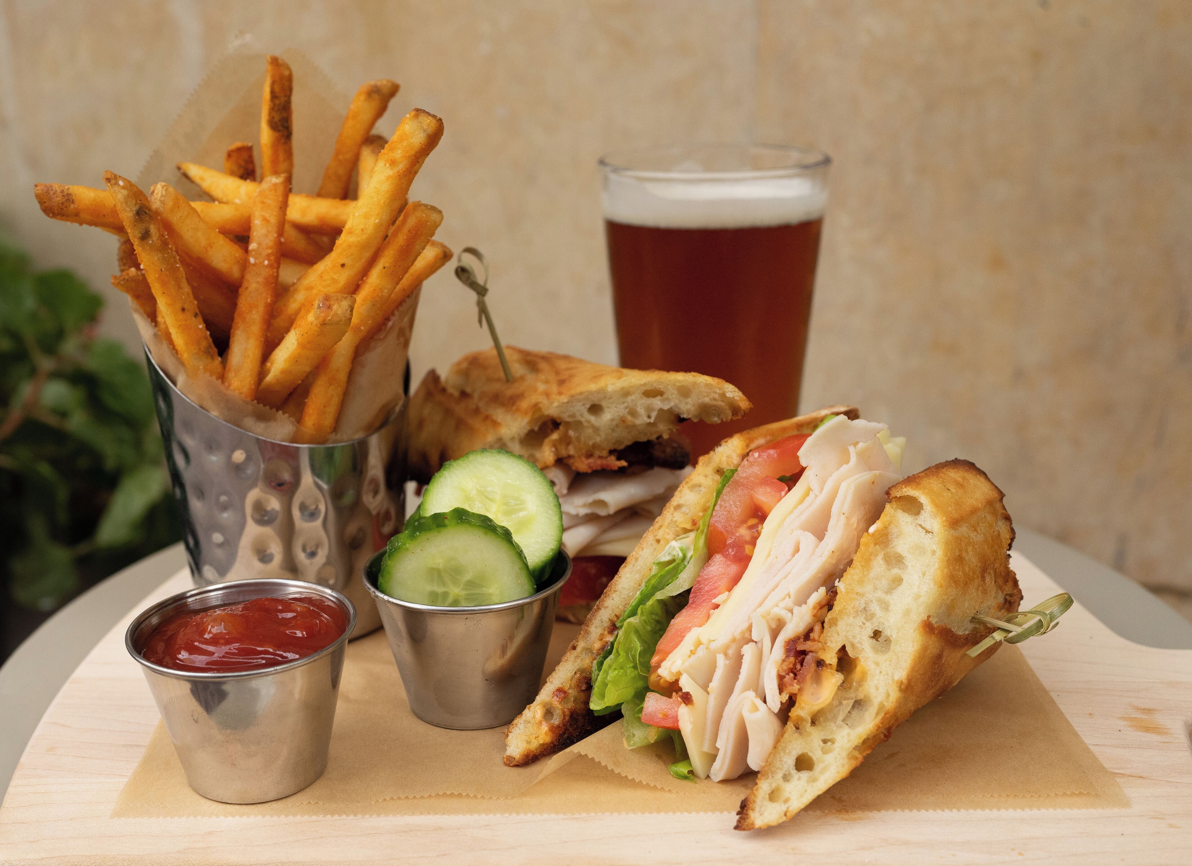 A sandwich with lettuce, tomato, and a side of fries, accompanied by a drink and ketchup.