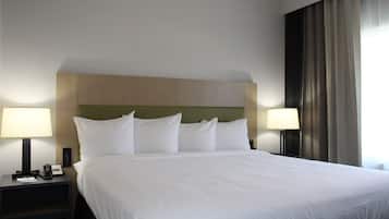A hotel room with a large bed, two bedside tables, a lamp on each, and a view of a curtain.