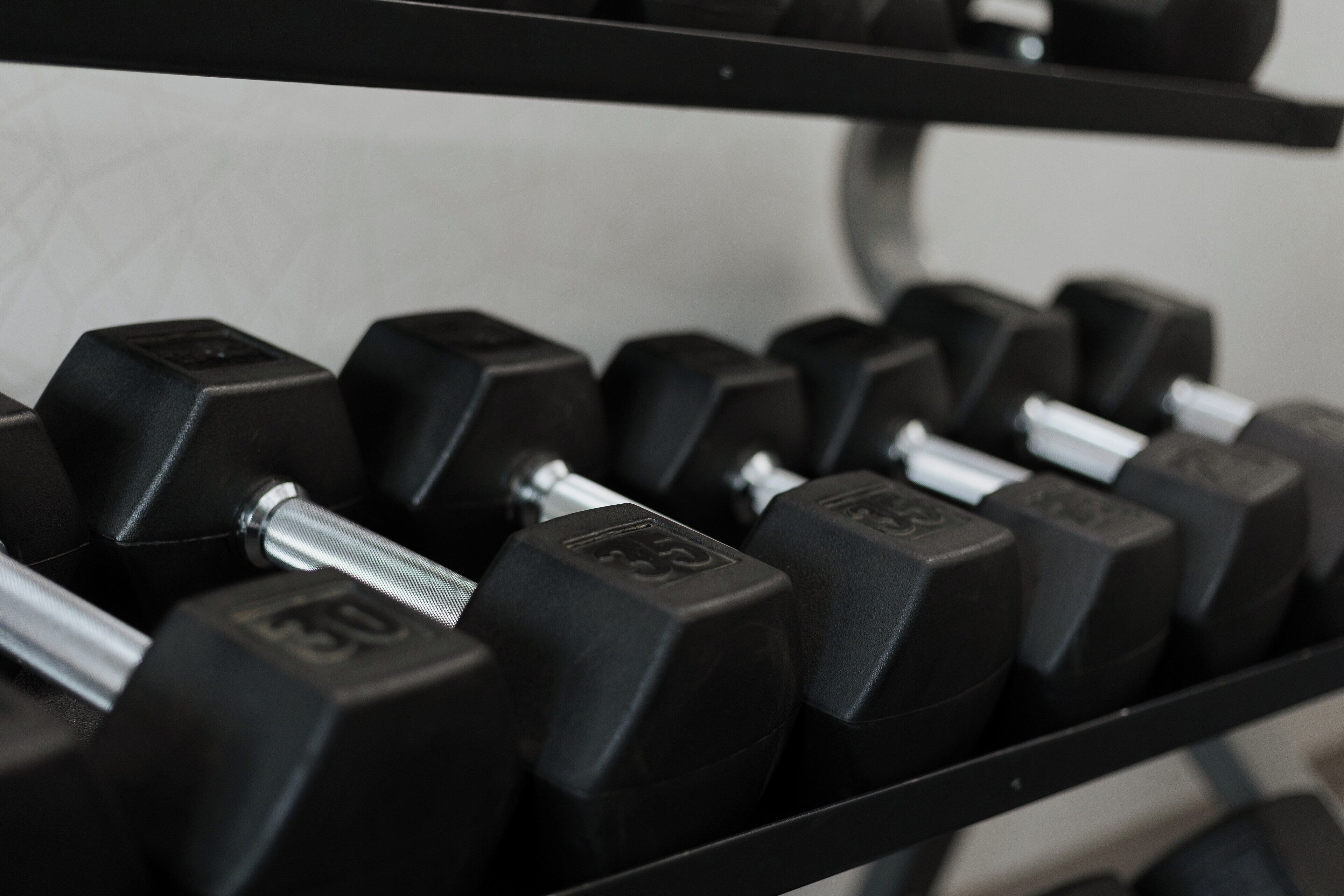 A close-up of a set of black dumbbells with visible weight markings.
