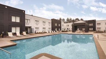 Een seizoensgebonden buitenzwembad en ligstoelen