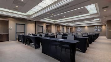 A conference room with rows of tables and chairs, a carpeted floor, and a ceiling with skylights.