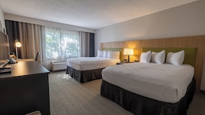 A hotel room with two beds, a desk, and a chair.