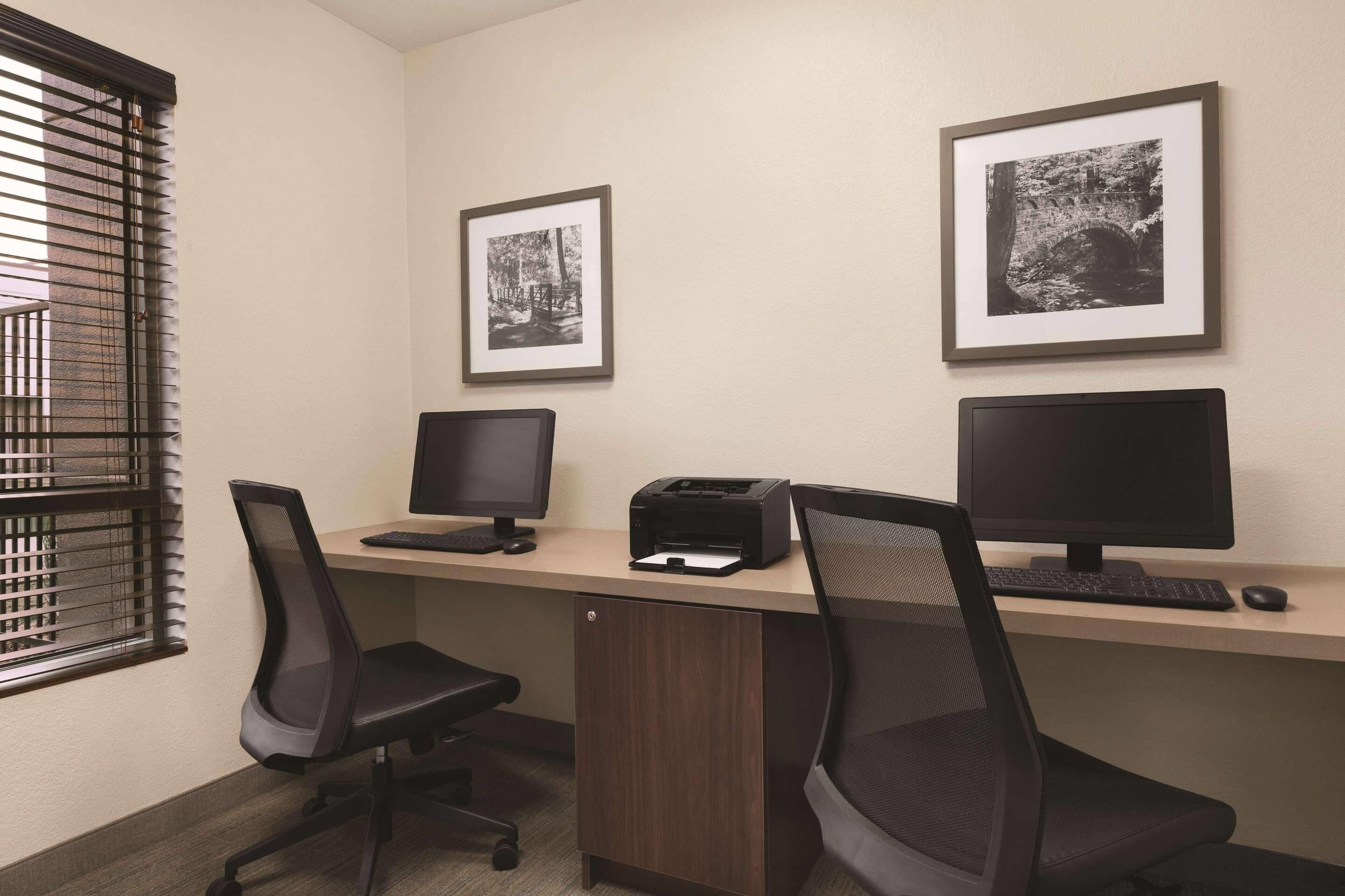Un espace de travail équipé de deux écrans, d’une imprimante et de deux chaises de bureau.
