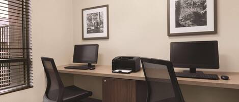 A workspace with two monitors, a printer, and two office chairs.