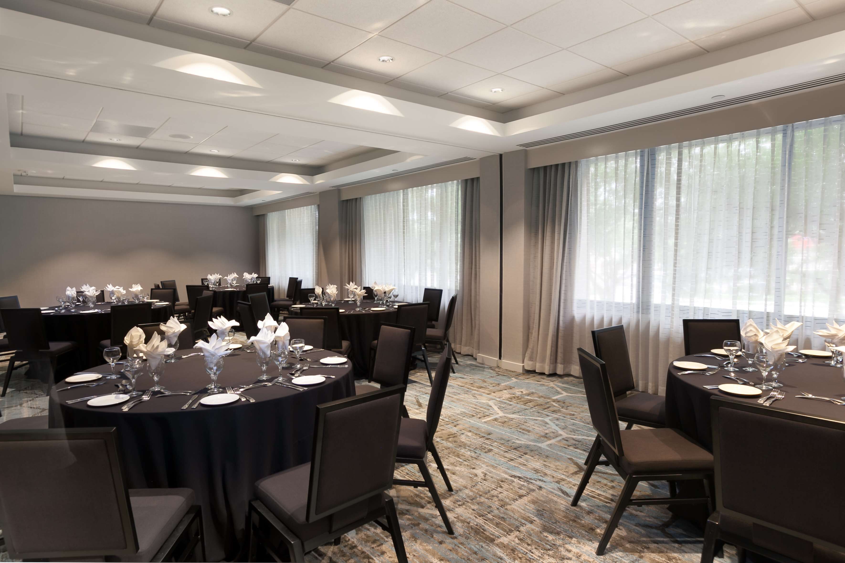 A conference room with round tables, chairs, and floral centerpieces.