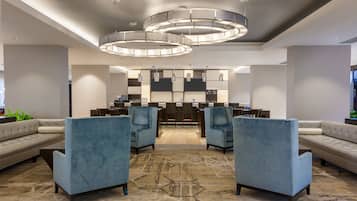 A modern lobby with a seating area, a reception desk, and a patterned carpet.