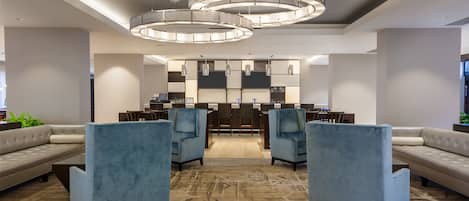 A modern lobby with a seating area, a reception desk, and a patterned carpet.