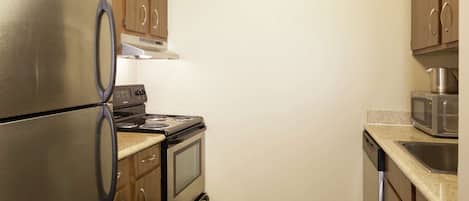 Una cocina compacta con electrodomésticos de acero inoxidable, armarios de madera y encimera de granito.