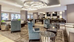 Un moderno vestíbulo de hotel con zonas de estar, una recepción y un bar.